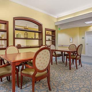 A well-furnished dining room with wooden tables and chairs, featuring elegant decor and carpeting.