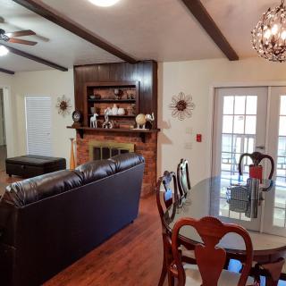 A cozy living and dining area featuring a leather sofa, fireplace, and a chandelier, with french doors leading outside.