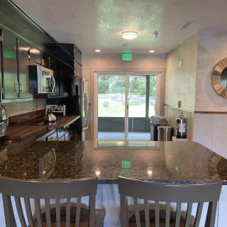 A modern kitchen interior featuring a large countertop and bar stools with a clear view of the outside through sliding doors.
