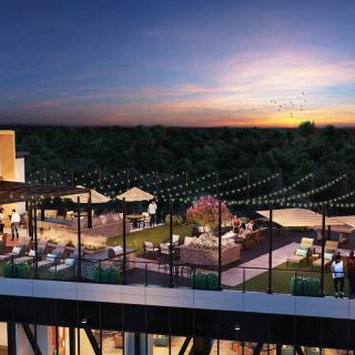 A lively rooftop scene at sunset with cozy outdoor seating and decorative string lights.