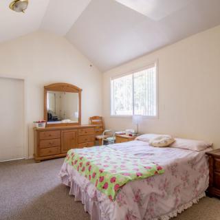 A cozy bedroom with a bed, dresser, and large window.