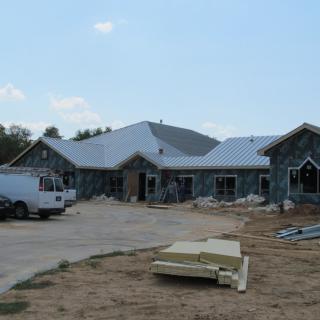 A house under construction with visible roofing and construction materials on site.