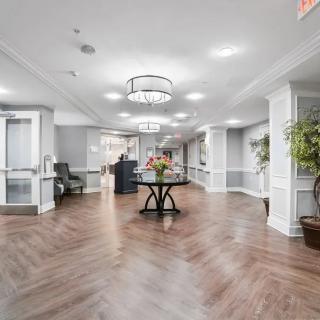 A modern and elegant lobby with stylish flooring, centered around a decorative table with flowers and illuminated by chandeliers.