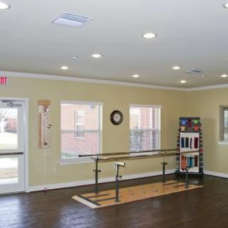 A physical therapy room with parallel bars and exercise equipment.