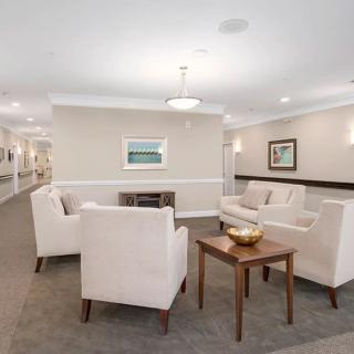 A modern living room with white chairs and a coffee table, featuring neutral decor.