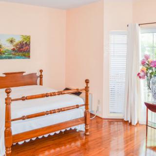 A cozy bedroom featuring a wooden bed, hardwood flooring, and floral accents.