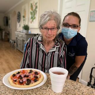 A caregiver and an elderly woman enjoying a meal together.