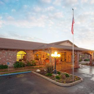 A welcoming residential building at sunset, featuring well-maintained landscaping and an American flag.