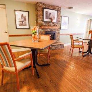 A cozy dining area featuring wooden floors and a fireplace, complemented by stylish chairs and decorative artwork.