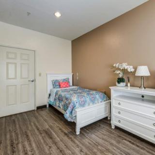 A cozy bedroom with a single bed, wooden flooring, and white furniture.