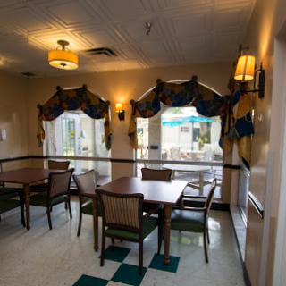 A cozy dining area with wooden tables, comfortable chairs, and large windows allowing natural light to brighten the space.
