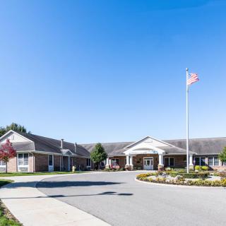 A well-maintained institutional building with a flagpole and clean landscaping under a clear blue sky.
