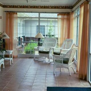 A cozy sunroom with wicker chairs and large glass windows letting in natural light.