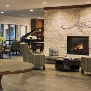 A modern lobby area featuring a fireplace, piano, and comfortable seating.