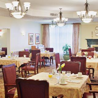 Elegant dining room with neatly arranged tables and chairs, adorned with chandeliers.