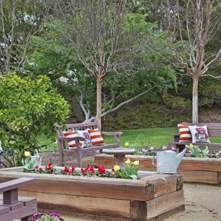 A peaceful garden setting with planter boxes, colorful flowers, and comfortable seating.
