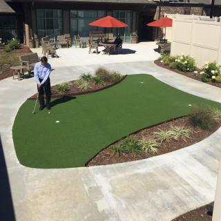 A person practicing putting on a well-maintained outdoor putting green.