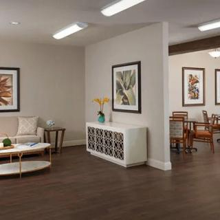 A modern interior featuring a living room with seating and art-adorned walls, leading into a dining area.