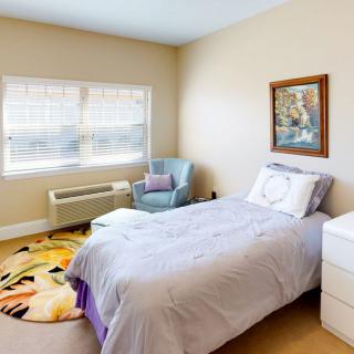 A cozy bedroom with a single bed, chair, and decorative painting.