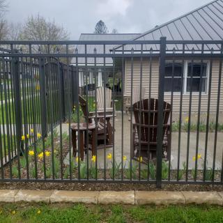 A fenced patio area with wooden chairs and a garden in front of a house.