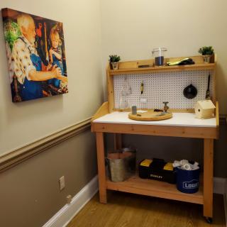 A cozy hobby corner featuring a wooden workbench equipped with tools and supplies, alongside a colorful painting on the wall.