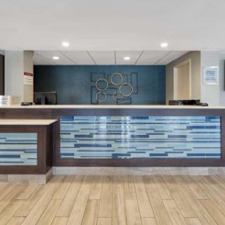 A modern hotel reception area featuring a stylish check-in desk with a blue and wood design.