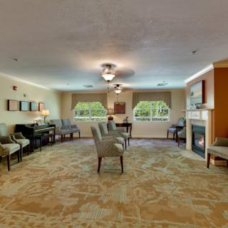 A spacious living room with elegant furniture and a fireplace, featuring large windows that let in natural light.