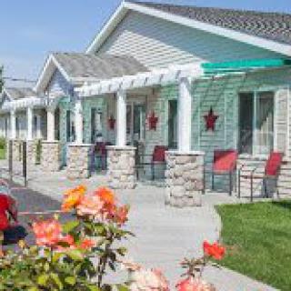 A quaint motel exterior with a row of units, adorned with star decorations and accompanied by a garden with blooming flowers.