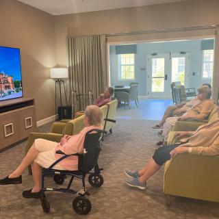 A group of elderly people watching television in a comfortable room.