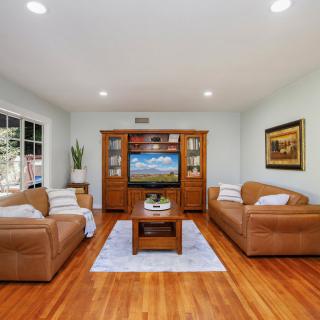 A cozy living room with leather sofas, a wooden coffee table, and a TV entertainment unit on a polished wood floor.