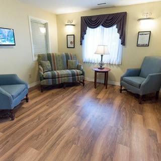 A cozy living room with a couch, two armchairs, and a table lamp on wood flooring.