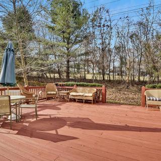 A spacious wooden deck with outdoor furniture and an umbrella, surrounded by trees.