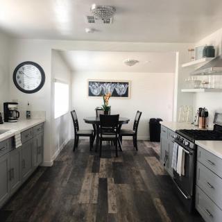 A modern kitchen with an adjacent dining area featuring wood flooring and a sleek, open layout.