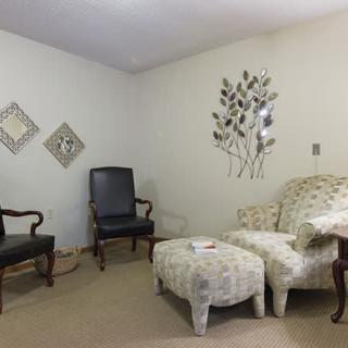 A cozy living room with various chairs, a sofa, an ottoman, and decorative wall art.