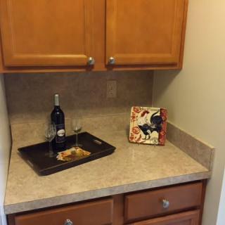 A kitchen corner with a countertop, cabinets, and wine decor.