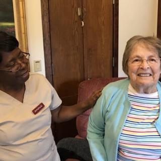 A cheerful moment shared between a caregiver and an elderly woman, highlighting companionship and care.
