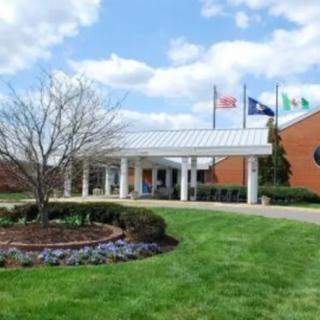 A building entrance with flags and landscaped gardens under a partly cloudy sky.
