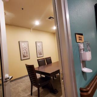 A view into a professional meeting room with a table and chairs, decorated with framed art.