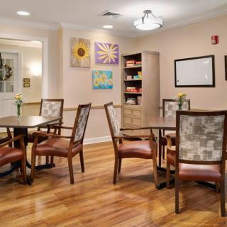 A cozy dining area with wooden flooring, decorated walls, and neatly arranged tables and chairs.