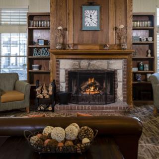 A cozy living room with a lit fireplace, flanked by bookshelves and comfortable seating.