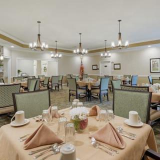 An elegant dining room with neatly arranged tables and chandeliers.