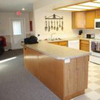 A kitchen with a central island, wooden cabinets, and various appliances.