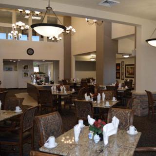 A cozy dining area with neatly arranged tables and chairs, featuring elegant lighting and decor.