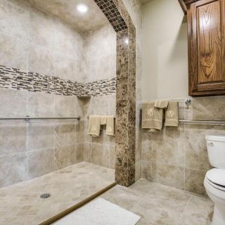 A modern bathroom with a tiled walk-in shower, towel racks, and a wooden cabinet.
