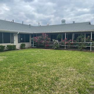 A view of a building with a well-maintained lawn and overcast sky.