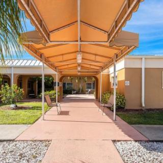 An entrance with an awning leading into a building, surrounded by landscaping.