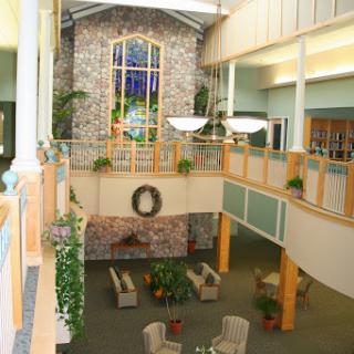 A spacious and welcoming lobby with a combination of stone elements and natural light, featuring comfortable seating and greenery.