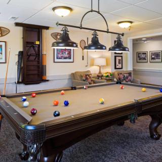 A cozy game room featuring a classic billiard table, stylish lighting, and framed artwork.
