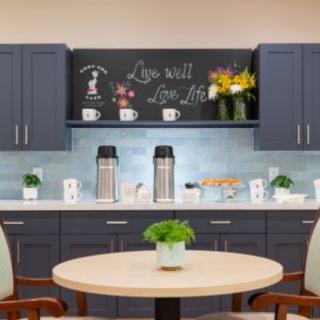 A modern kitchen setup featuring a coffee station with a decorative chalkboard and potted plants.