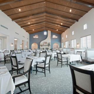 An elegant restaurant interior with white tablecloths and a wooden ceiling.